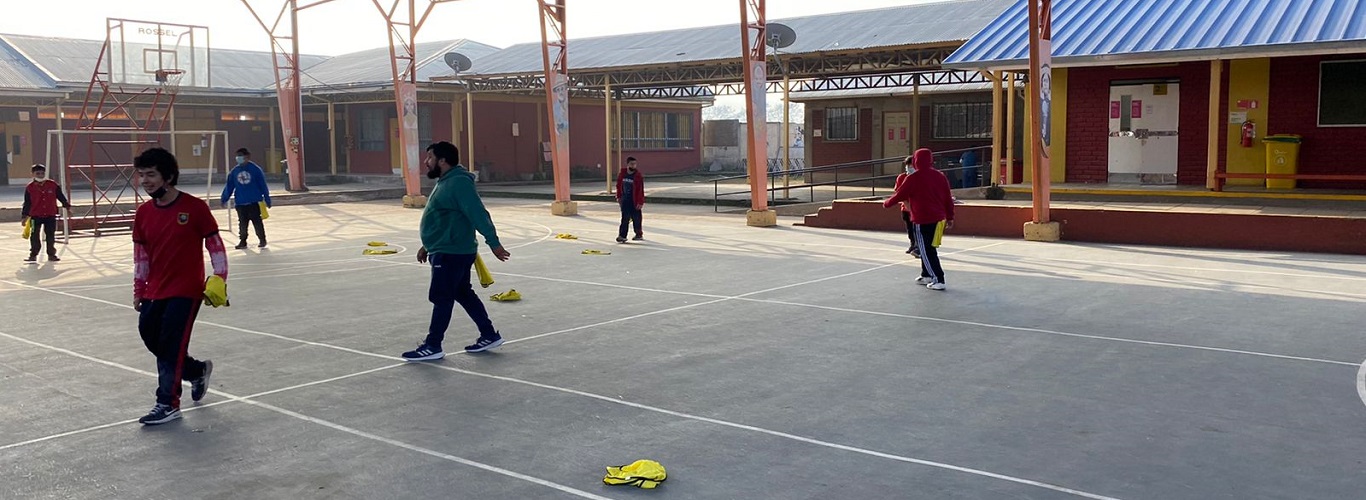 Rear view of kids raising hands while teacher explaining the fun